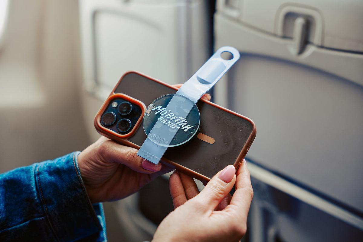 Person holding a the Mo'Bettah Magsafe phone holder on an iphone inside a plane.