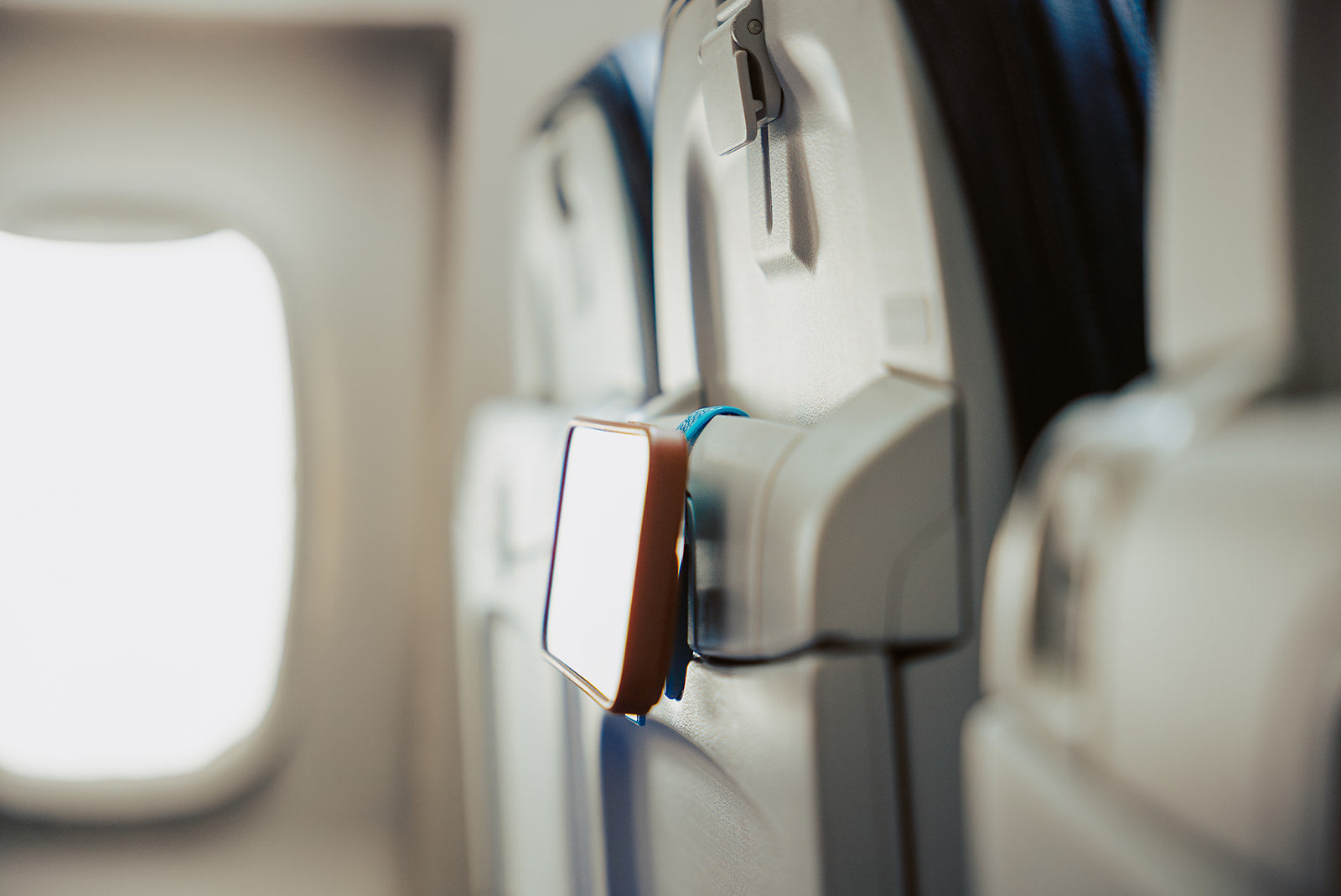Blue Mo'bettah Airplane Phone Holder securely holding an iPhone on an airplane seat pocket during a flight