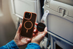 Traveler holding a clear Mo'bettah Airplane Phone Holder next to a MagSafe compatible iPhone before attaching it