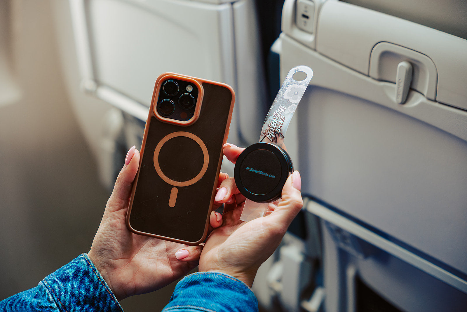 Traveler holding a clear Mo'bettah Airplane Phone Holder next to a MagSafe compatible iPhone before attaching it