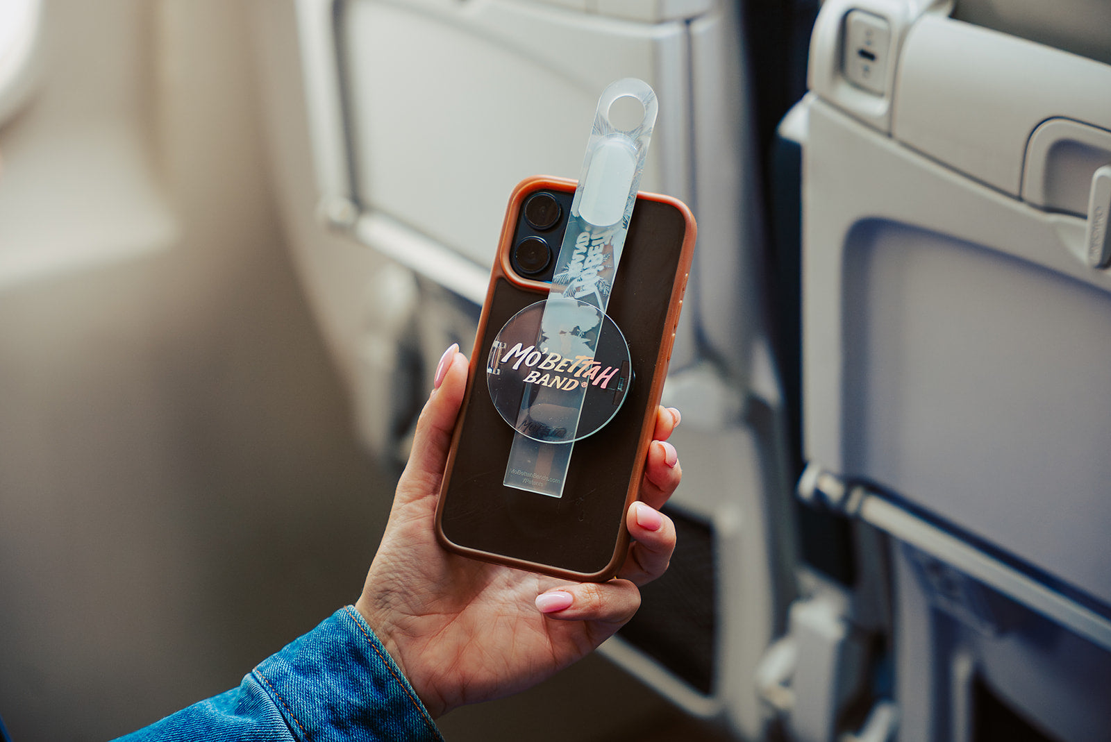 Traveler showing a clear Mo'bettah Airplane Phone Holder on a MagSafe compatible iPhone