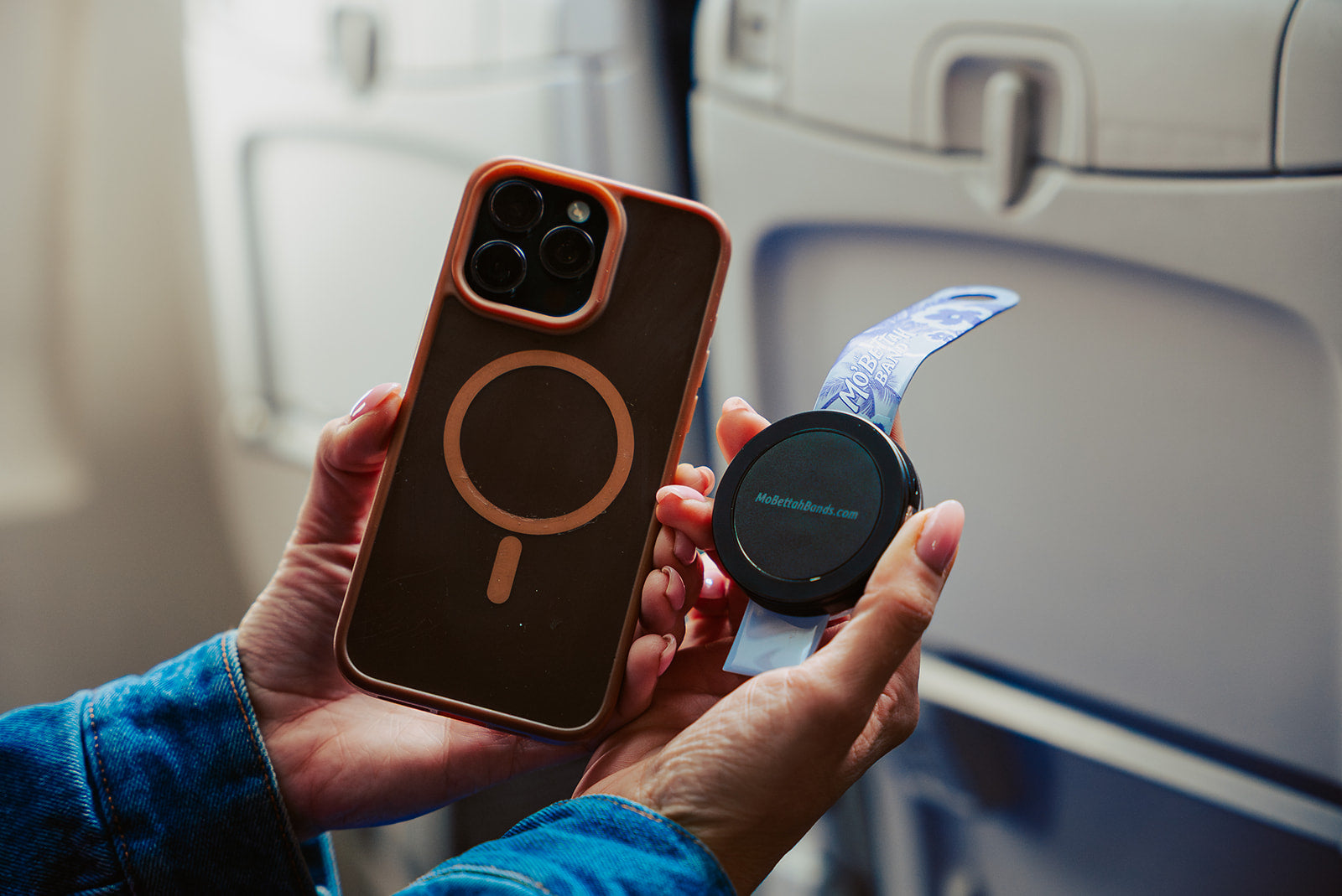 Traveler holding a Purple Mo'bettah Airplane Phone Holder next to a MagSafe compatible iPhone before attaching it
